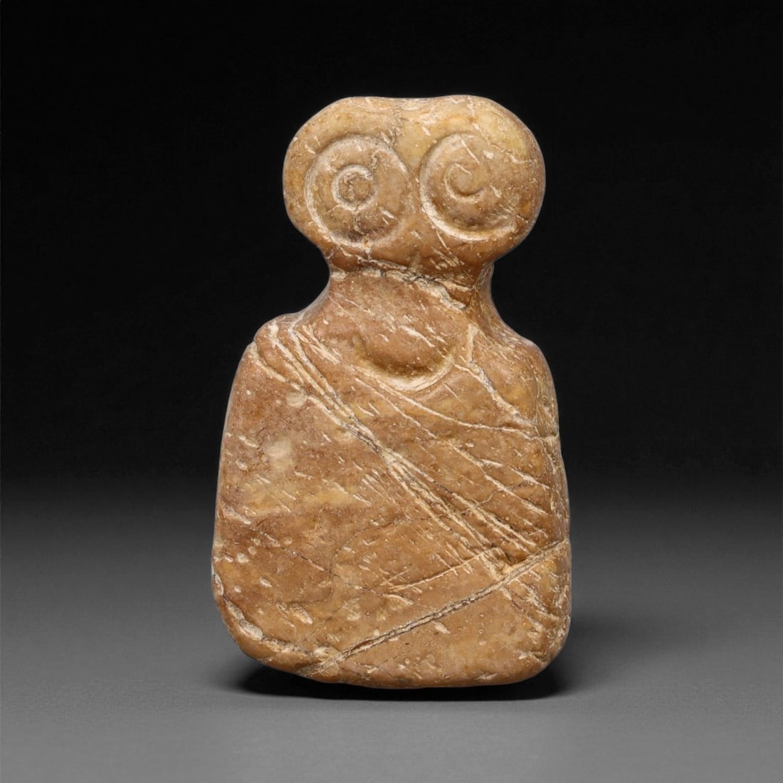 A Near Eastern Stone Eye Idol, 4th-3rd Millennium BCE, 4LA: Carved from light brown stone with fine surface veining, the object has a flat, tapering lower body and a rounded upper section featuring two large circular eyes defined by concentric incisions around