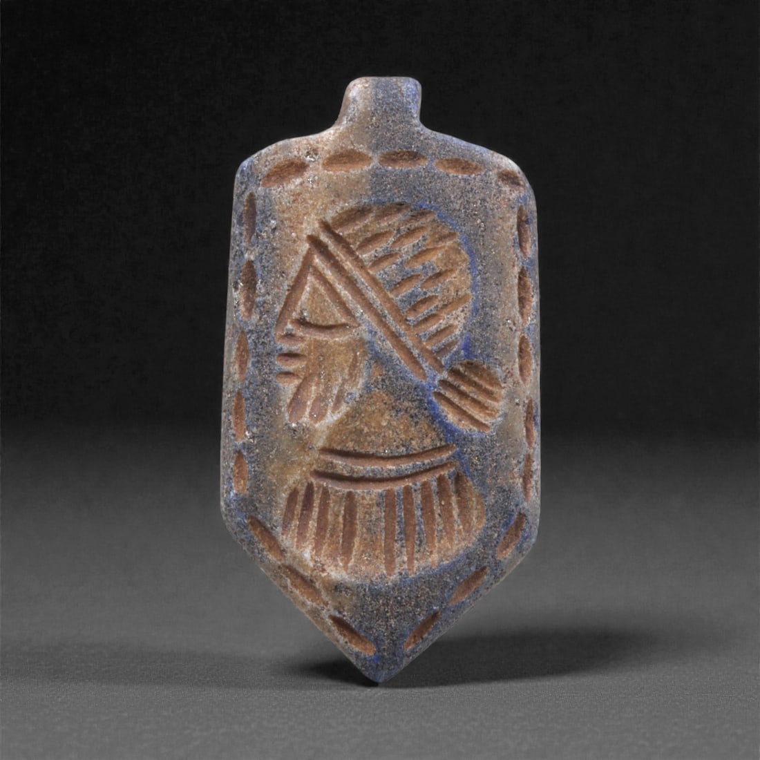 A Sasanian Lapis Lazuli Amulet, 3rd-7th Century CE, 3.8cm, 37Q: Carved from deep blue lapis lazuli with visible lighter inclusions and natural granular texture, the object is finished with a flat reverse and a front surface worked in low relief. The carving is exe