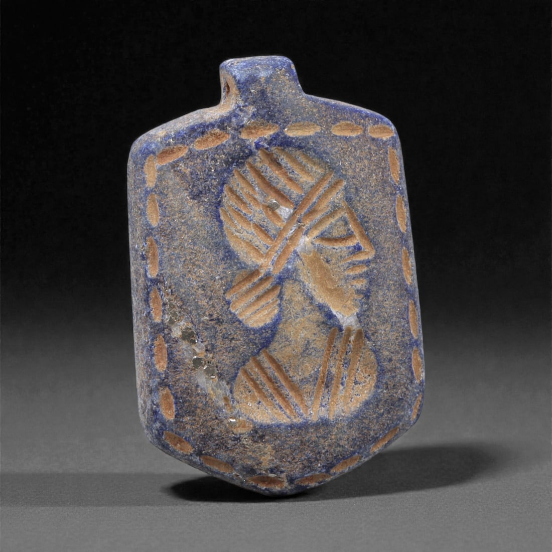 A Sasanian Lapis Lazuli Amulet, 3rd-7th Century CE, 4cm, 53K: Carved from deep blue lapis lazuli with visible lighter inclusions and natural granular texture, the object is finished with a flat reverse and a front surface worked in low relief. The carving is exe