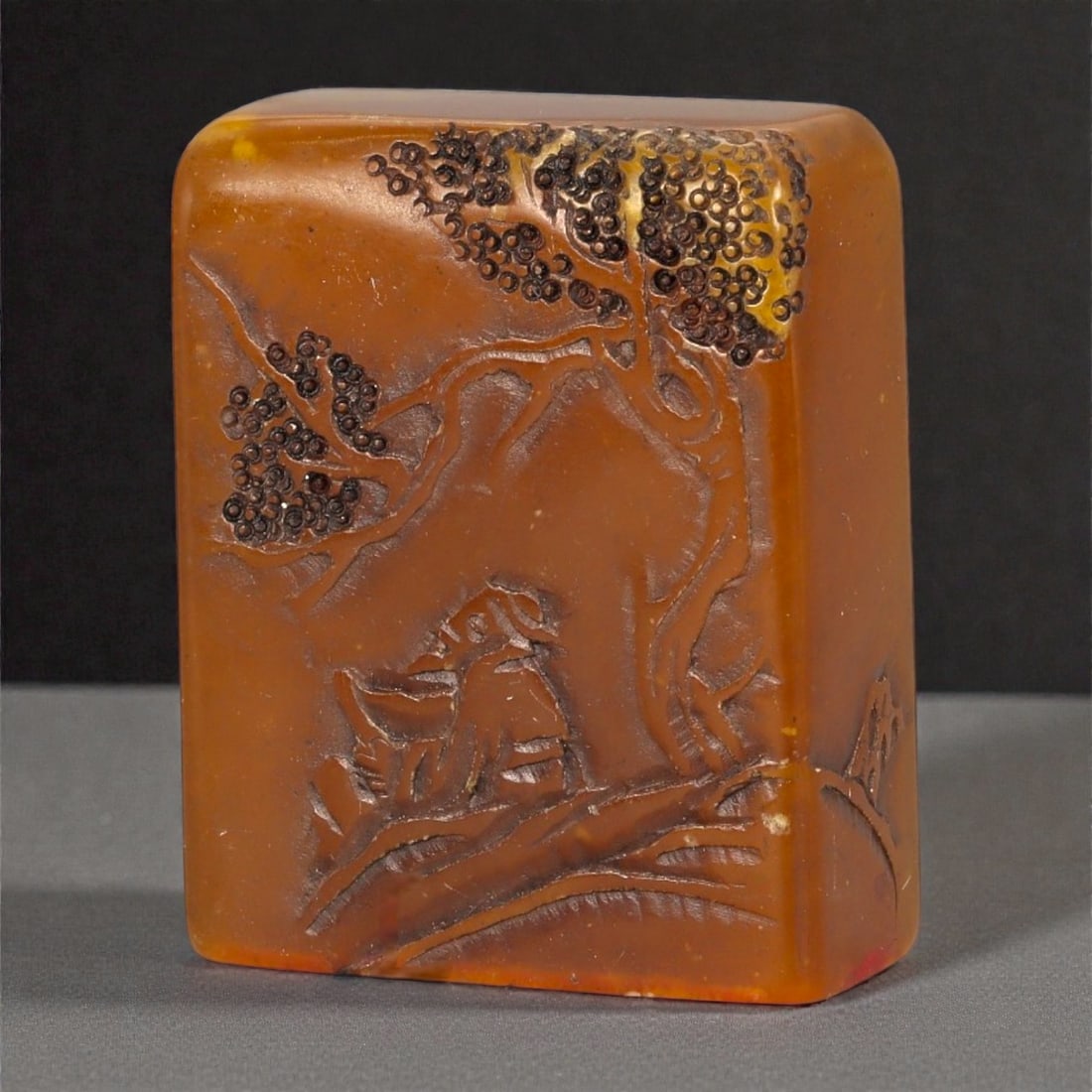 A Chinese Shoushan Stone Seal, 20th Century, 6FA: Carved from warm amber-toned Shoushan stone with areas of translucency and darker natural inclusions, the seal is formed as a compact rectangular block with softly rounded edges. One face is incised i
