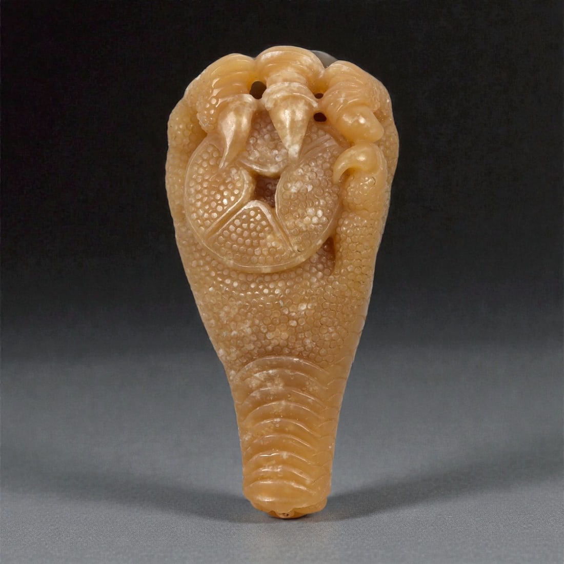 A Chinese Nephrite Jade Claw Grasping Coin Pendant, 20th Century, 50FB: Carved from pale honey-brown nephrite jade with areas of translucency and natural mottling, the pendant is worked in the form of a claw grasping a circular coin. The surface is extensively textured wi