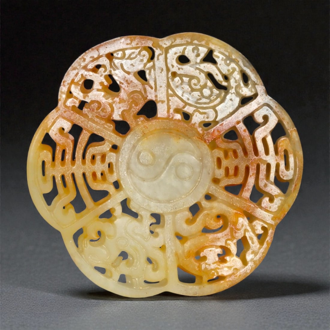 A Chinese Nephrite Jade Openwork Roundel, 20th Century, 23FA: Carved from pale celadon nephrite jade with areas of russet and honey-colored alteration, the roundel is worked in openwork relief and divided into four lobed sections radiating from a central circula