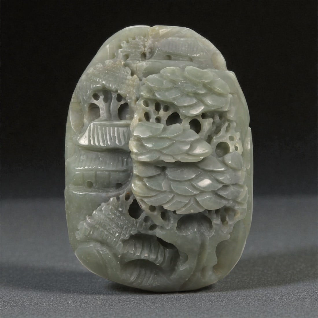 A Chinese Jade Openwork Landscape Plaque, 20th Century, 21YA: Carved from pale gray-green jade with areas of translucency and minor natural inclusions, the object is formed as a vertically oriented plaque with extensive openwork carving. The composition presents