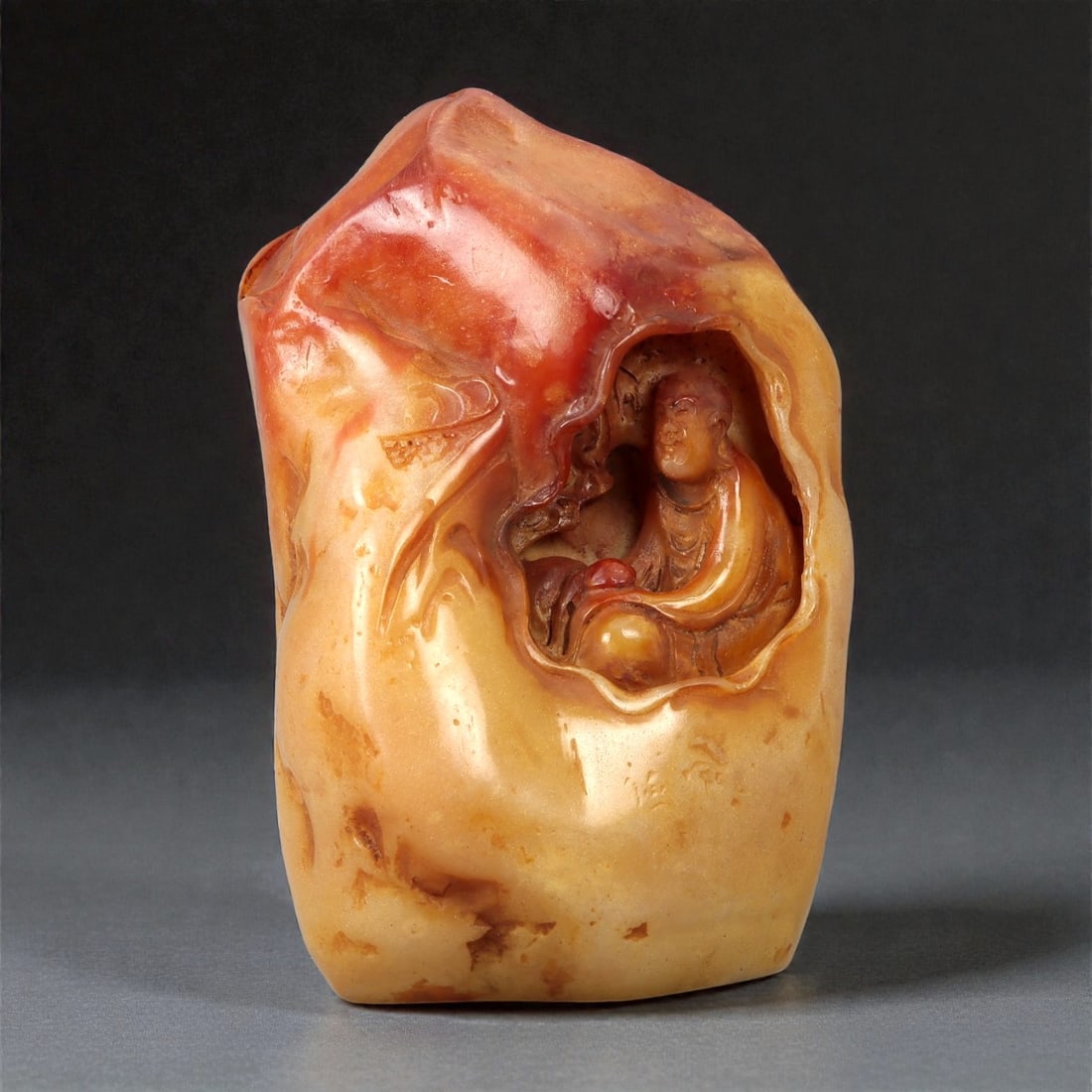A Chinese Shoushan Stone Seal, 20th Century, 26FD: Carved from Shoushan stone displaying variegated tones of pale yellow, ochre, and russet, the seal is worked as a vertical block with an irregular, naturalistic exterior. One face is carved in relief
