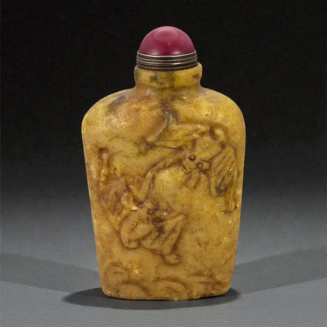 A Chinese Jade Snuff Bottle, Qing Dynasty, 18th-19th Century, 3FA: Carved from a pale olive-green jade with areas of darker mottling and natural inclusions, the snuff bottle is of flattened rectangular form with rounded shoulders and a short cylindrical neck. One mai