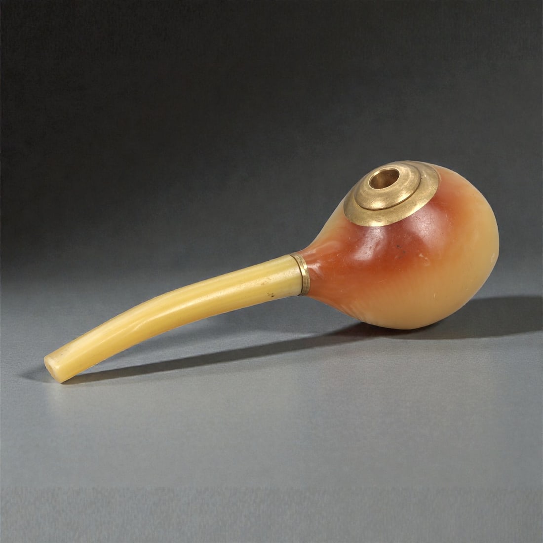 A Chinese Hetian Jade Smoking Pipe, 20th Century, 47FC: Carved from pale celadon Hetian jade with areas of warm amber and honey-brown coloration, the pipe is composed of a globular bowl joined to a gently curved stem. The bowl is smoothly hollowed and fitt