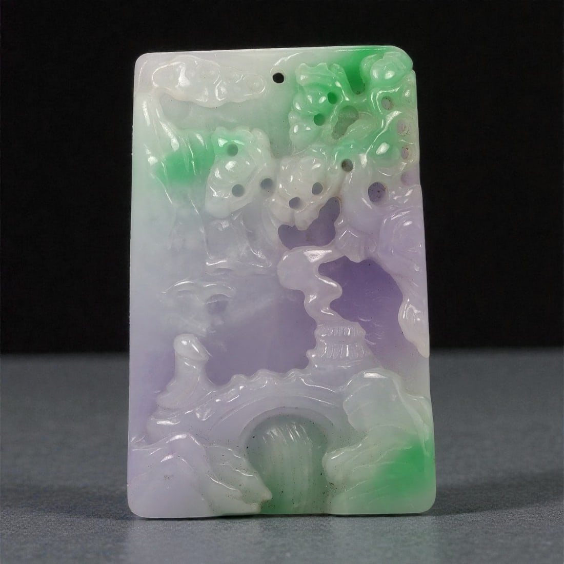 A Chinese Jadeite Jade Rectangular Plaque, 20th Century, 92FC: Carved from translucent jadeite jade with pale lavender, milky white, and vivid green color zoning, the object is worked as a rectangular plaque with relief decoration on the front and a flat reverse.