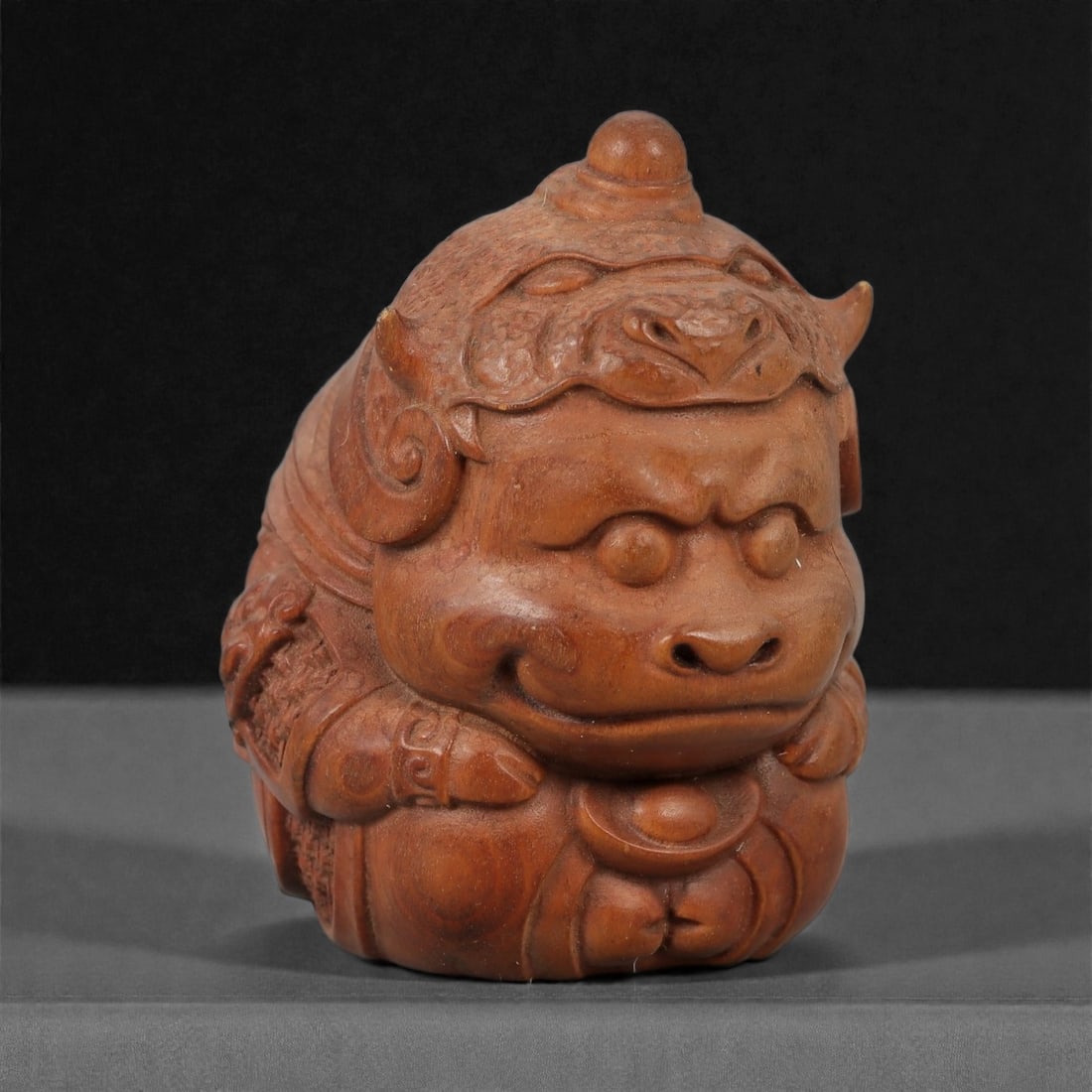 A Chinese Wood Mythical Beast Figure, 20th Century, 43FD: Carved from warm brown wood with a smooth, polished surface, the figure represents a seated mythical beast shown frontally with compact proportions. The head is modeled with pronounced brows, rounded 
