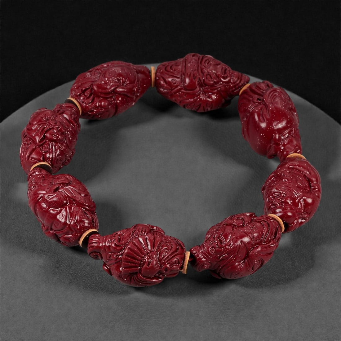 A Chinese Cinnabar Carved Bead Bracelet, 20th Century, 72YB: Composed of a continuous strand of large cinnabar lacquer beads, drilled and strung to form a circular bracelet. Each bead is carved in high relief with densely arranged scrolling floral and foliate m