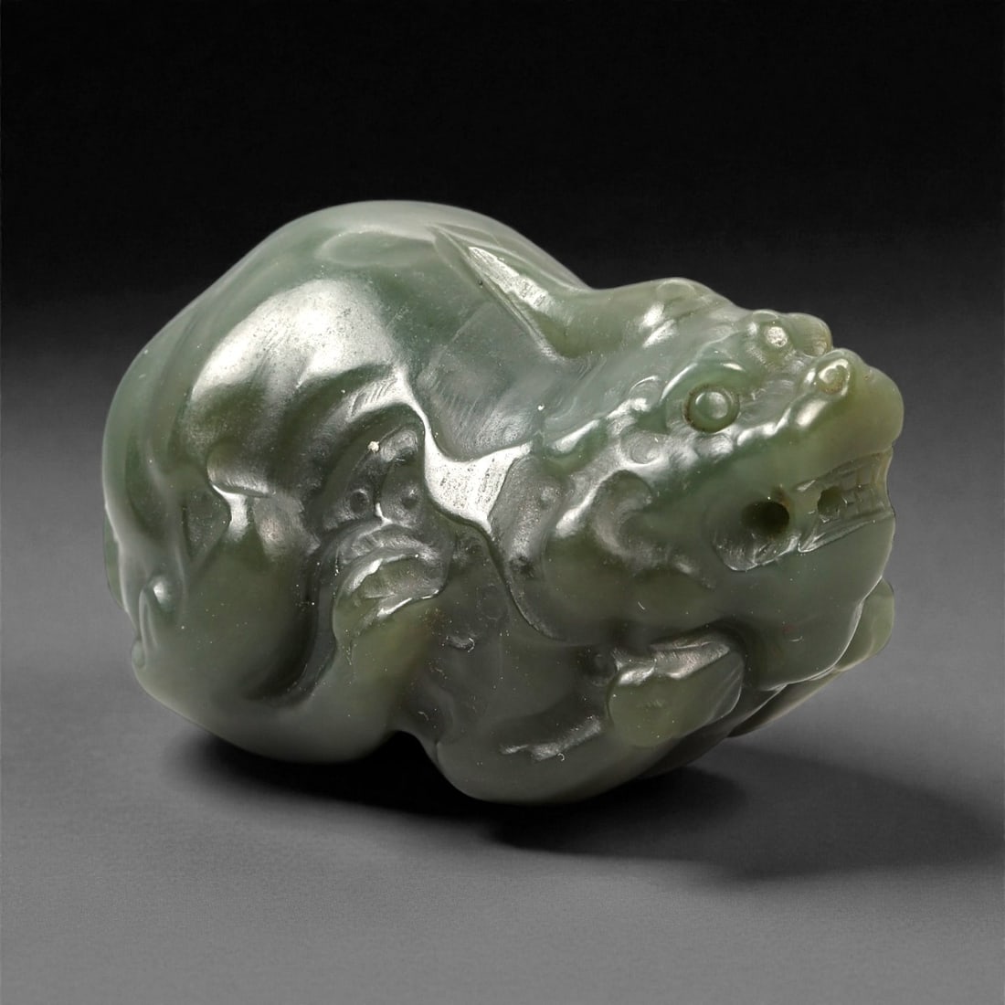 Chinese Jade Pixiu Beast - Carved Animal Figurine 4.2cm, 87ZC, 87ZC: Carved from translucent green jade with natural darker mottling, this small sculptural figure depicts a pixiu in a compact crouching posture. The carving is executed in the round, emphasizing a rounde