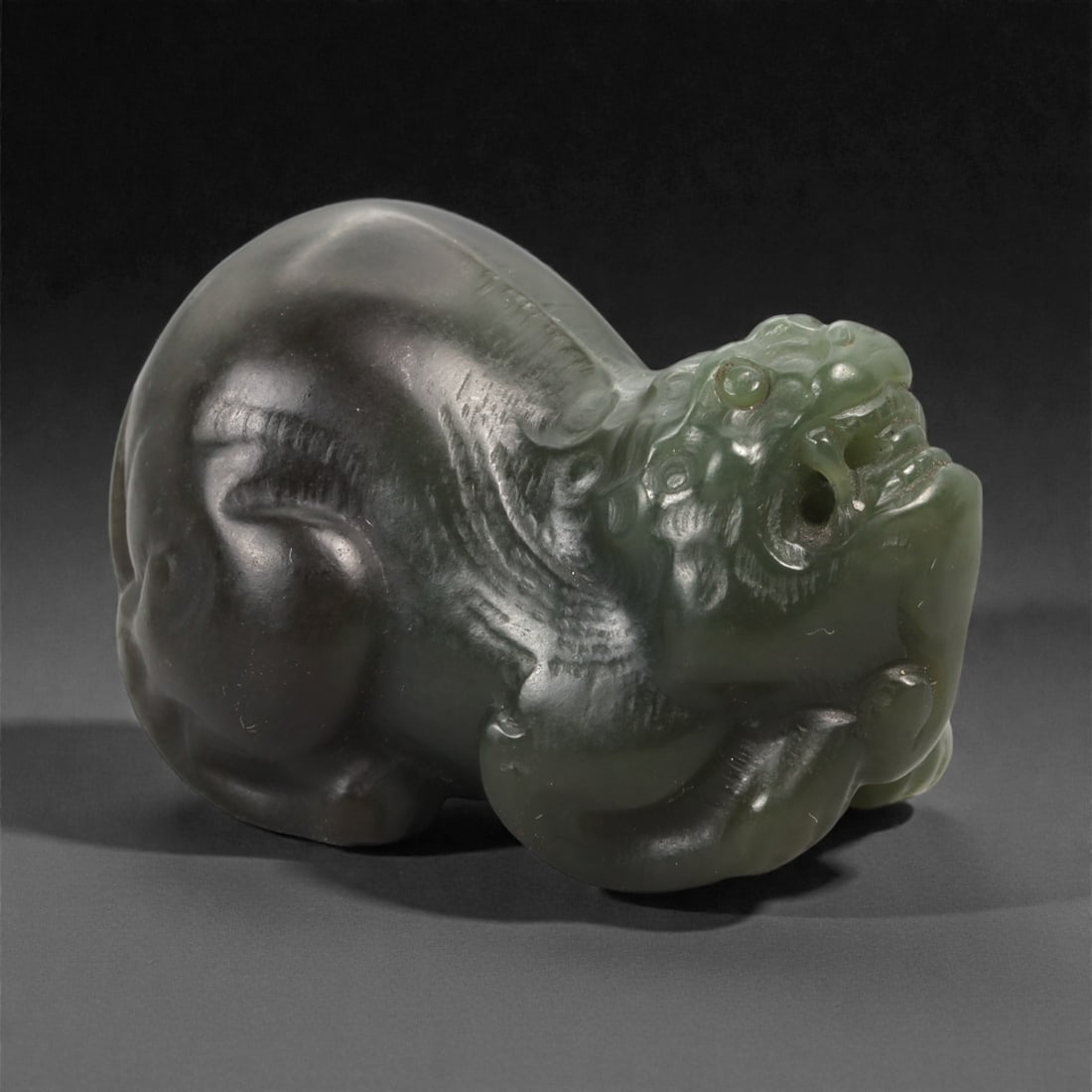 Chinese Jade Pixiu Beast - Carved Stone Figure, 54ZD: Carved from translucent green jade, this small sculpture depicts a recumbent pixiu rendered in the round, with smoothly polished surfaces and selectively incised details defining the head, haunches, a