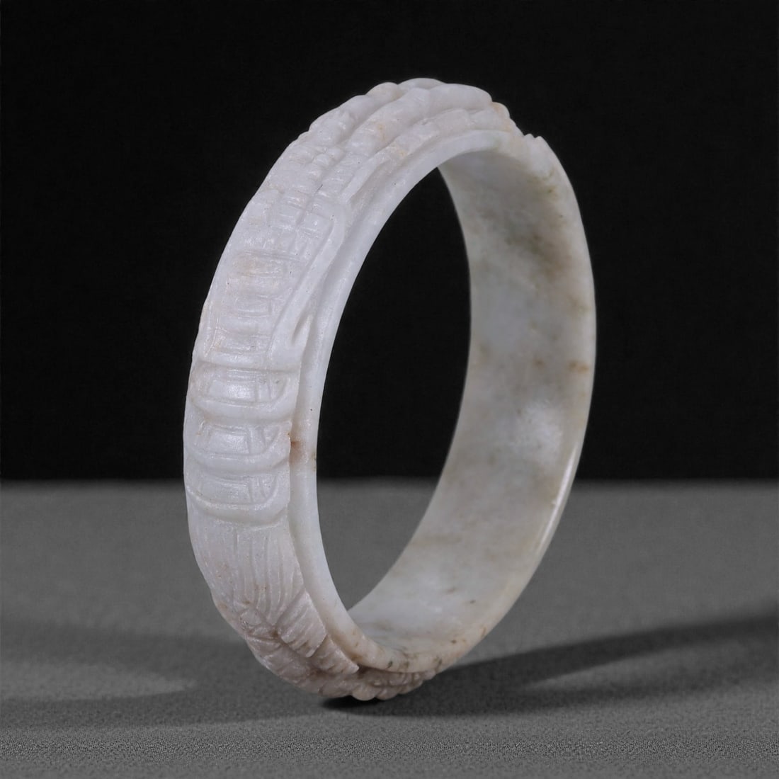 Carved White Jade Bangle - Chinese Style Bracelet, 37WE: The bangle is carved from pale white to light grey jade with soft translucency and scattered natural inclusions, polished to a smooth, even surface that highlights the stone's fibrous texture. The ext