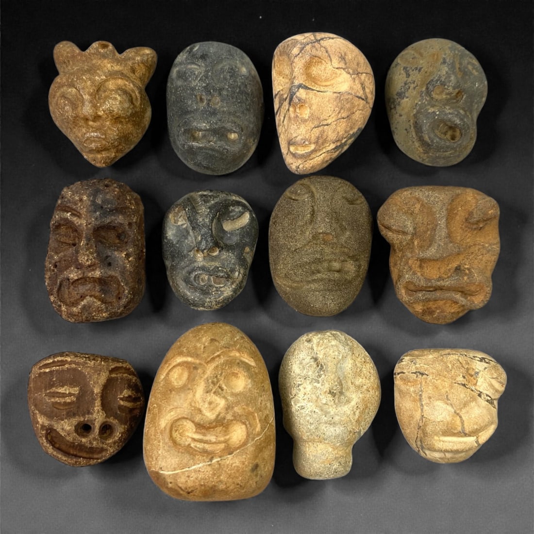 A Lot of Ancient Mediterranean Stone Maskettes, 12th-17th Century, 2-3.3cm, 43V: The group comprises lot of small maskettes carved from various stone types, including limestone and related sedimentary materials, displaying a range of natural tones from pale beige and ochre to dark
