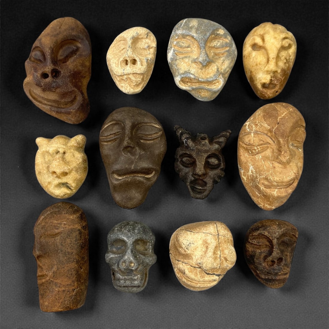 A Lot of Ancient Mediterranean Stone Maskettes, 12th-17th Century, 2.5-4cm, 41V: The group comprises lot of small maskettes carved from various stone types, including limestone and related sedimentary materials, displaying a range of natural tones from pale beige and ochre to dark