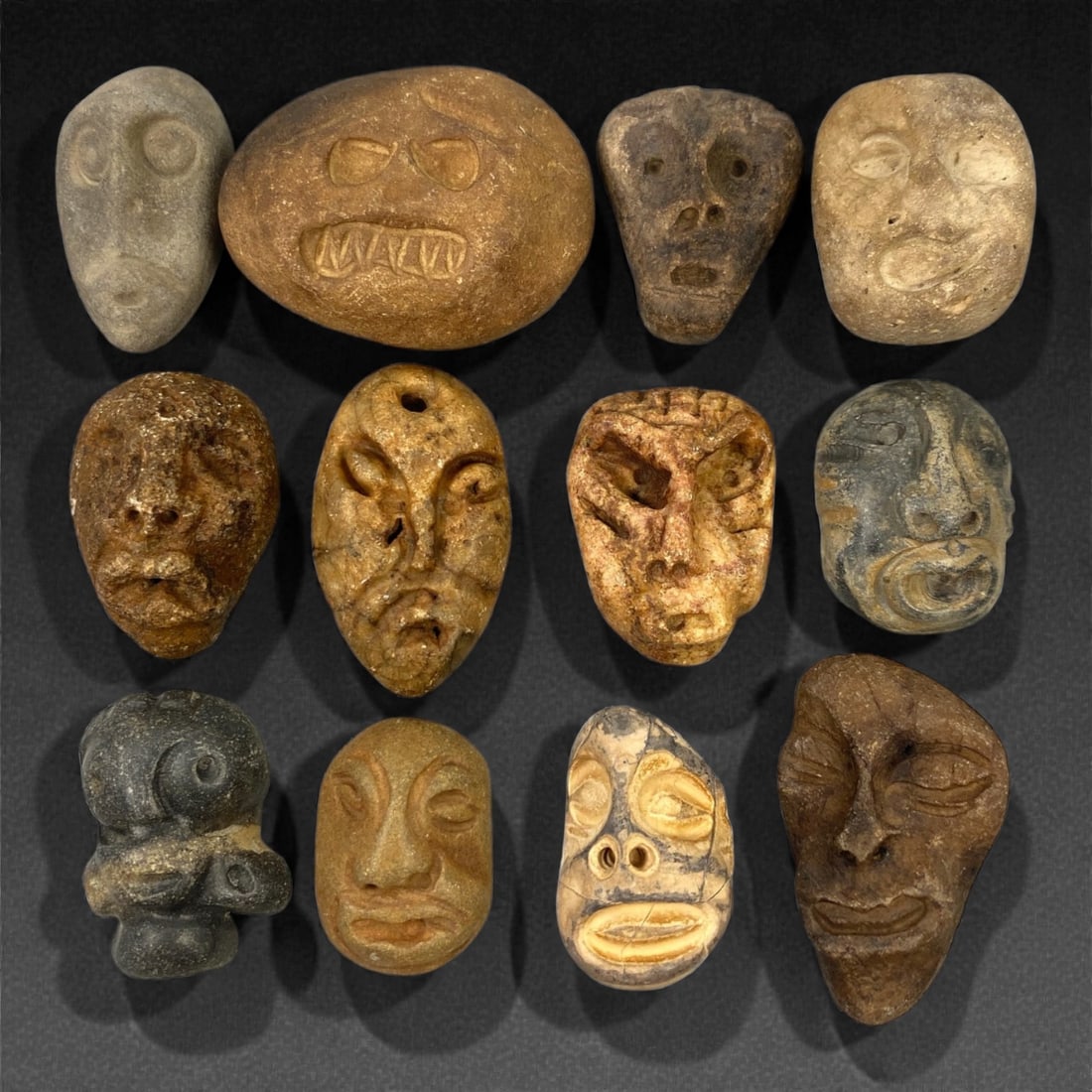 A Lot of Ancient Mediterranean Stone Maskettes, 12th-17th Century, 2.5-4cm, 39V: The group comprises lot of small maskettes carved from various stone types, including limestone and related sedimentary materials, displaying a range of natural tones from pale beige and ochre to dark
