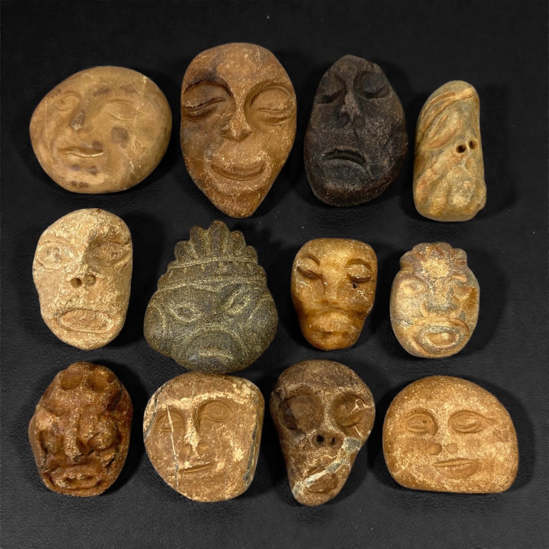 A Lot of Ancient Mediterranean Stone Maskettes, 12th-17th Century, 2.5-3.8cm, 35V: The group comprises lot of small maskettes carved from various stone types, including limestone and related sedimentary materials, displaying a range of natural tones from pale beige and ochre to dark