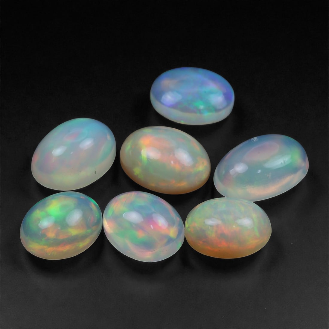 10.43 Carats Oval Cabochon Opal Lot - Natural Ethiopian Stones - 9 to 11mm, 59XA: This captivating set of seven Ethiopian opal cabochons glows with luminous internal fire, revealing a spectrum of radiant hues-neon green, flame orange, bright pink, and ocean blue-floating beneath so