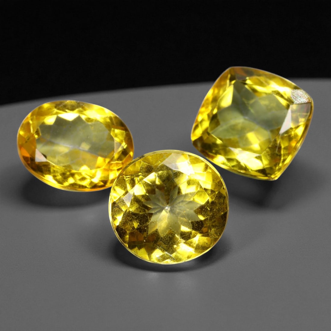 24.01 Carats Golden Yellow Topaz Trio - Natural Brazilian Stones - 1.2 to 1.4 cm, 13XE: This radiant trio of golden yellow topaz bursts with brilliance, each gem cut to maximize fire and light return across its faceted surface. The vivid hue sits at the heart of a warm golden spectrum, o