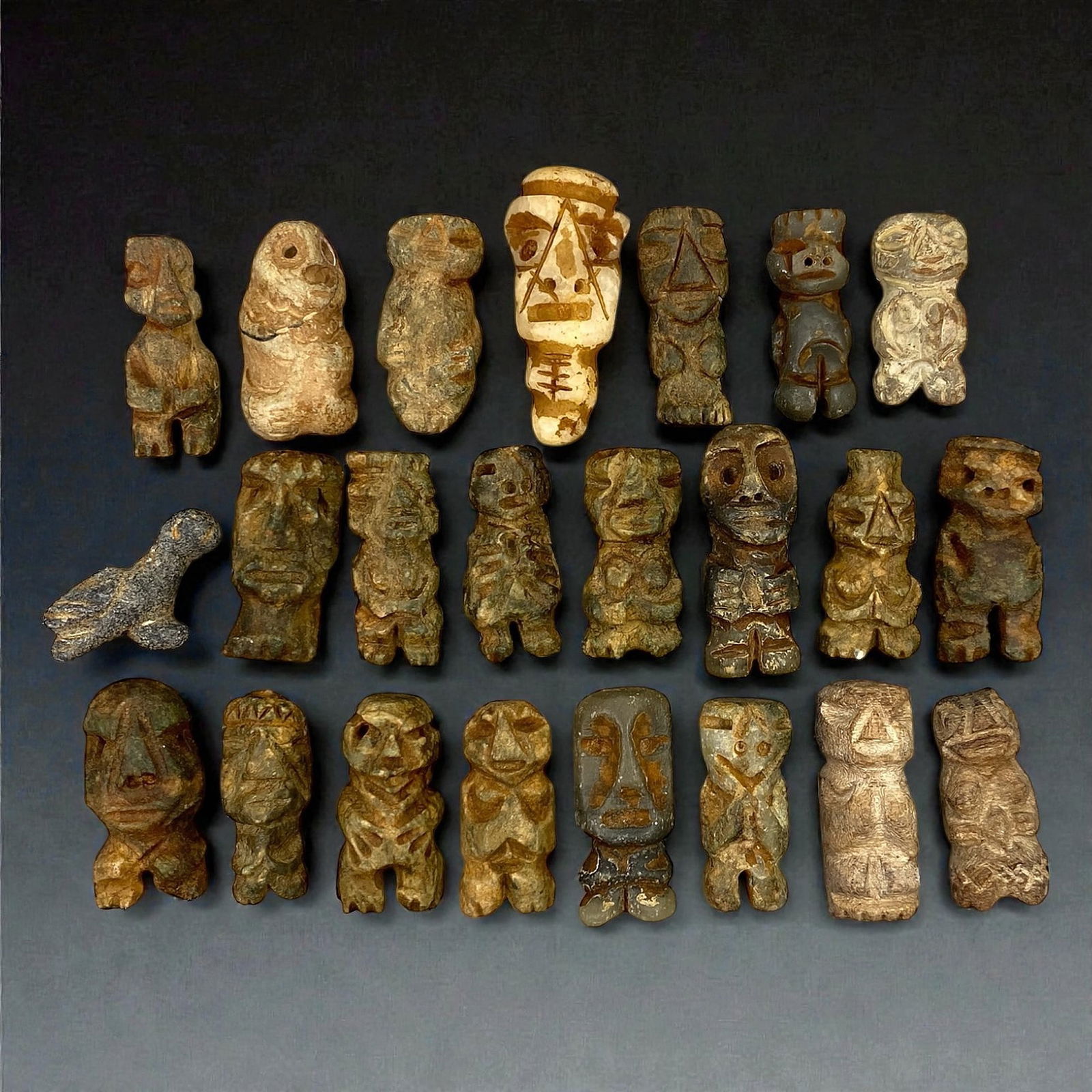 A Group of Taino Stone Anthropomorphic Idols, Late Pre-Columbian Period, Circa 1000-1500 CE, 68V: Comprising twenty-three small anthropomorphic stone idols carved from grey, brown, buff, and variegated stone, each figure is rendered in a compact, highly schematic manner characteristic of Taino scu