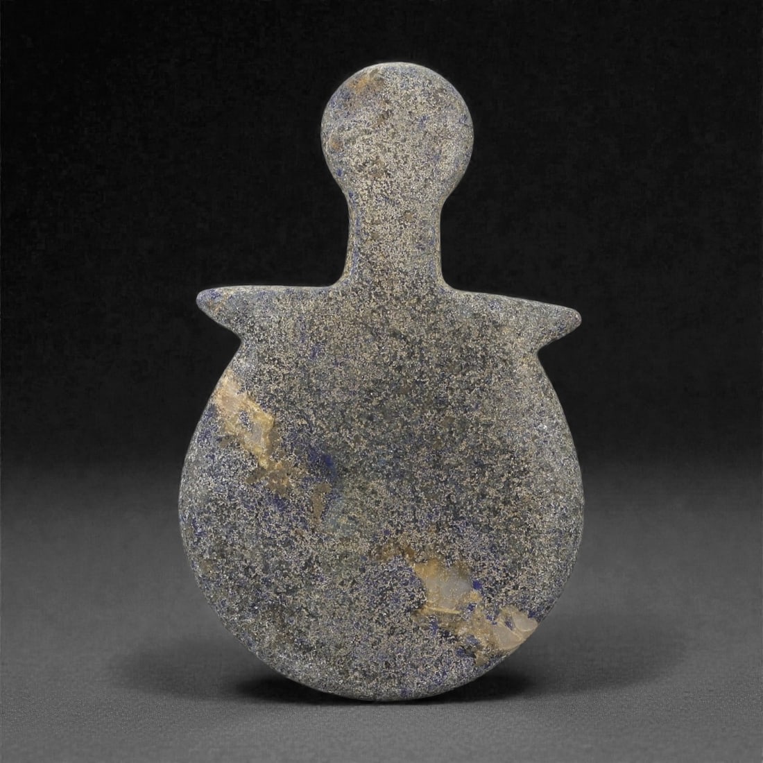An Ancient Bactria-Margiana Lapis Lazuli Idol, 21LM: Carved from mottled blue-grey lapis lazuli with natural veining, the idol is shaped as a flat, stylized anthropomorphic figure with a rounded head, a long tapering neck, and a broad, circular lower bo