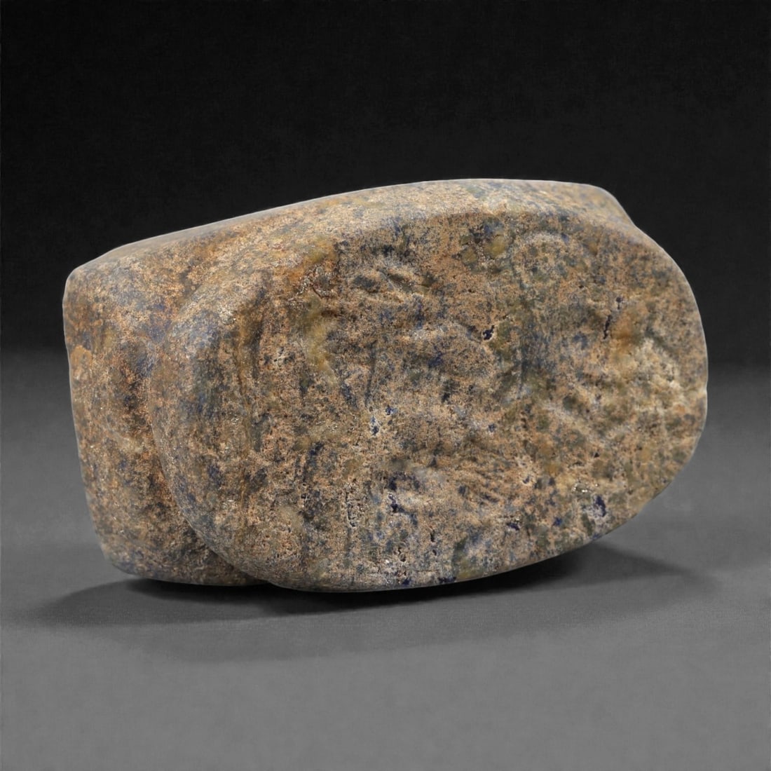 A Near Eastern Lapis Lazuli Stamp Seal, 3rd Millennium BCE, 32LD: Carved from mottled blue-grey lapis lazuli with natural inclusions, the seal is shaped with a triangular upper section rising from a rounded base. A circular perforation passes horizontally through th