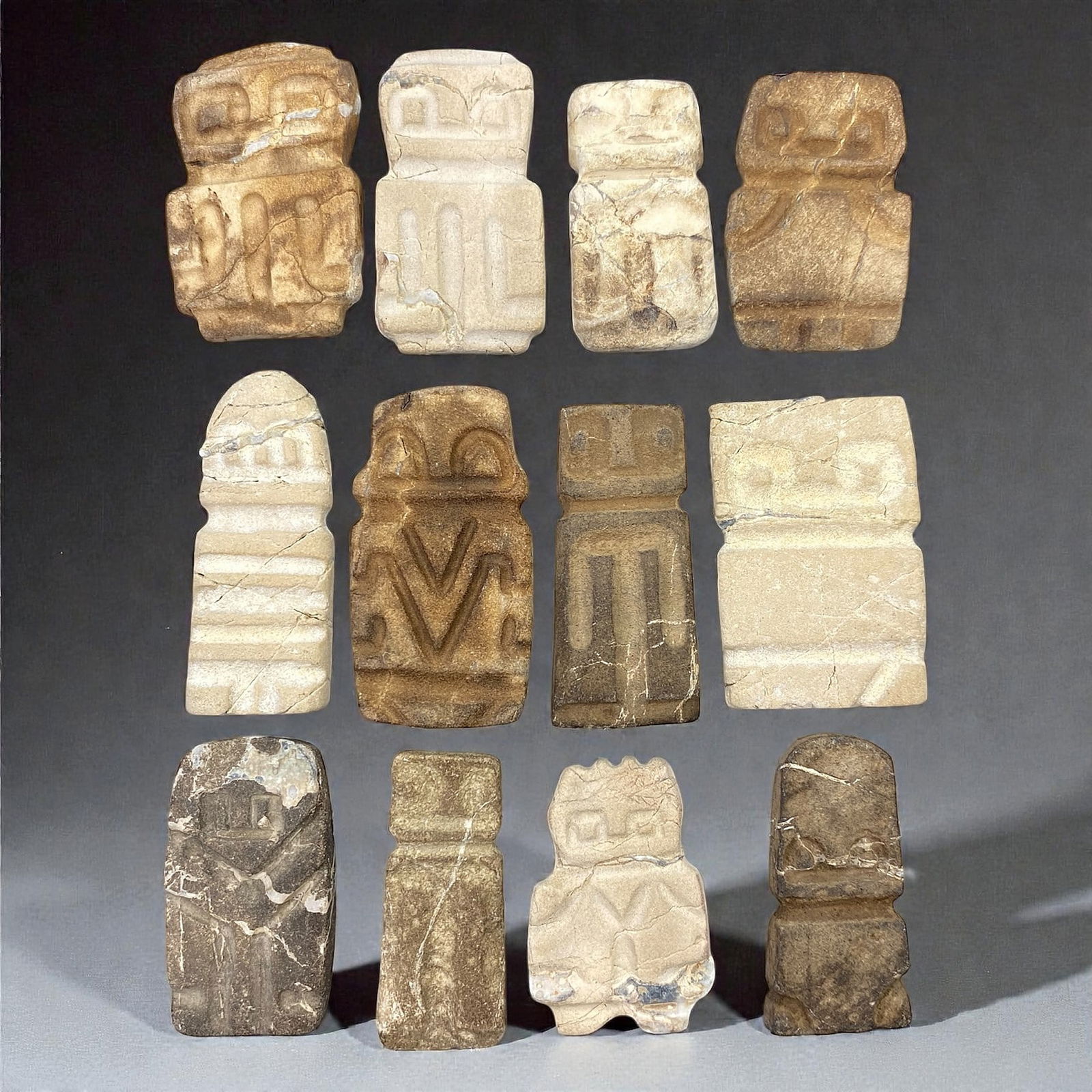 A Group of Valdivian Stone Anthropomorphic Figures, Circa 3500-1500 BCE, 71V: Comprising twelve small anthropomorphic stone figures carved from light beige, grey, and brown stone, each figure is rendered in a highly schematic, columnar form characteristic of Valdivian sculptura