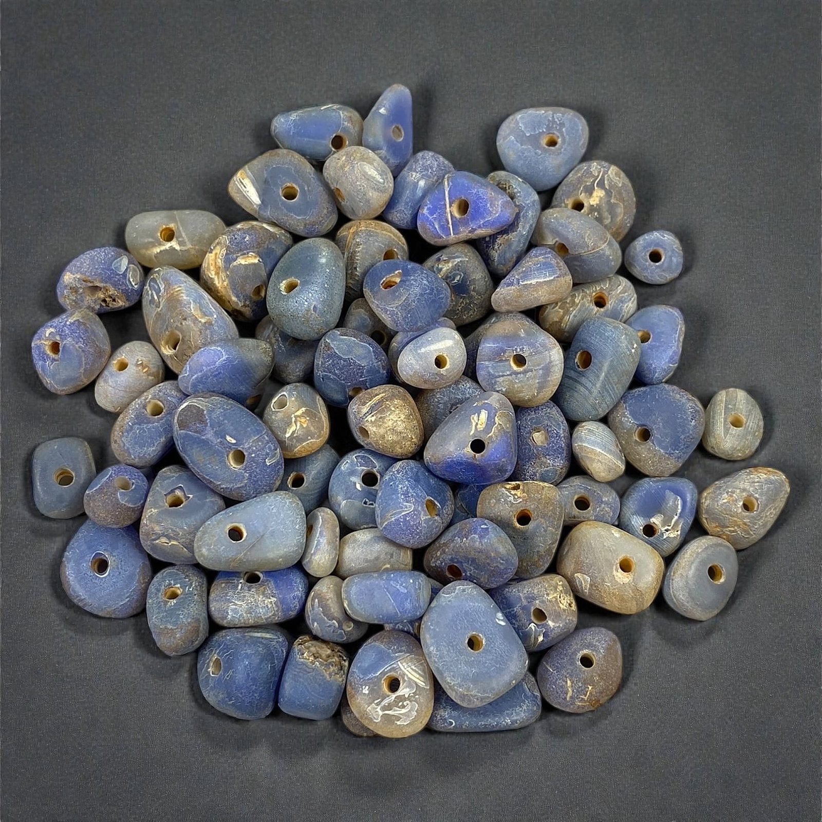 A Group of Mediterranean Chalcedony Trade Beads, Circa 6th-4th Century BCE, 66V: Comprising a large group of drilled chalcedony beads formed from translucent to opaque blue, grey-blue, and bluish-grey stone, each bead worked into rounded or slightly irregular forms with central pe