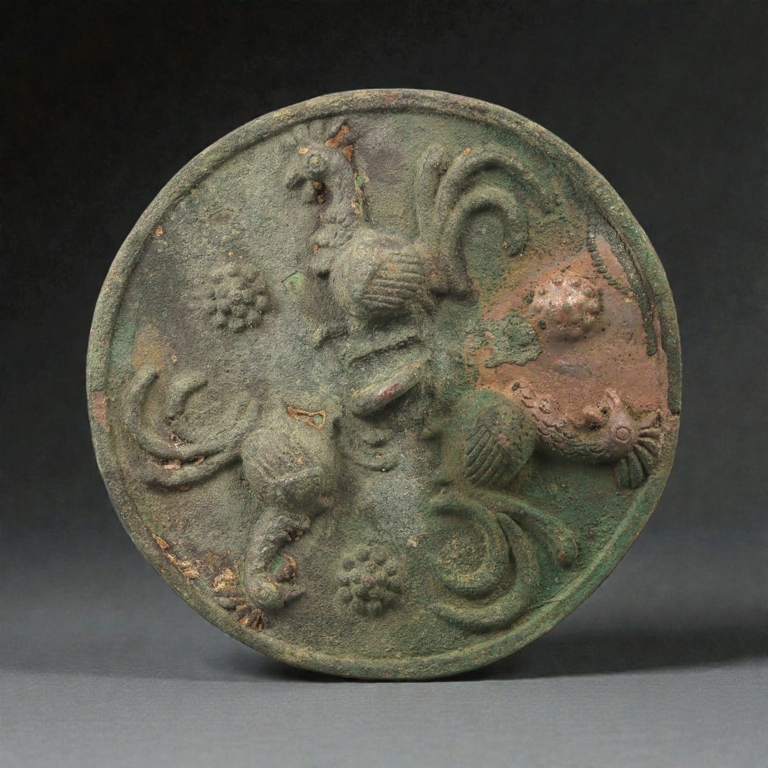A Sasanian Bronze Roundel with Birds in Relief, 5th-7th Century CE, 81LP: Cast in bronze as a circular plaque, the surface is modeled in low relief with four birds arranged around the central field. Each bird is rendered with a rounded body, short beak, and a raised, ridged