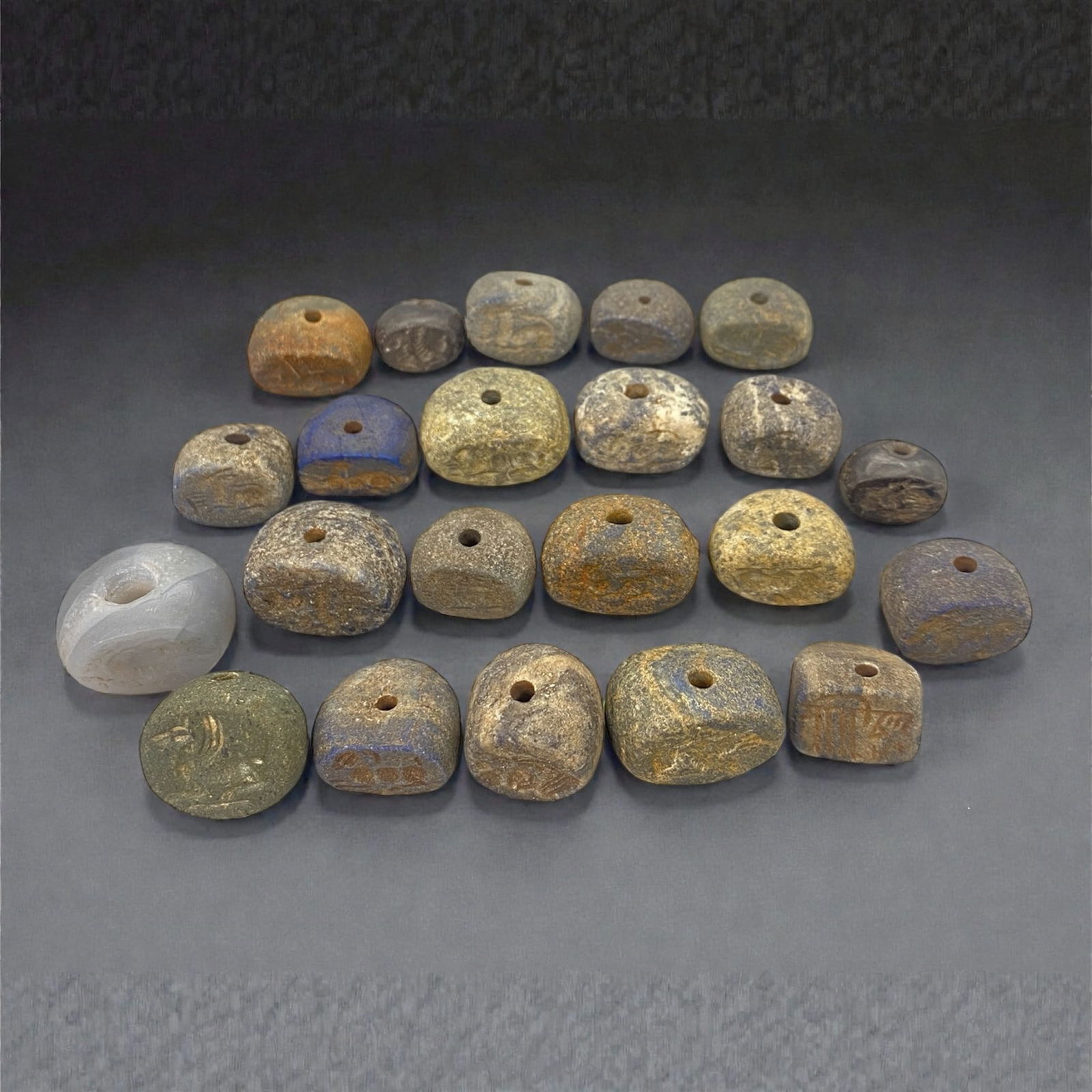 A Group of Sasanian Stone Stamp Seals, Circa 4th-7th Century CE, 12W: Comprising twenty-two stamp seals carved from various stone materials, including agate, chalcedony, and other fine-grained stones, the group presents predominantly rounded, domed, and squared forms, e