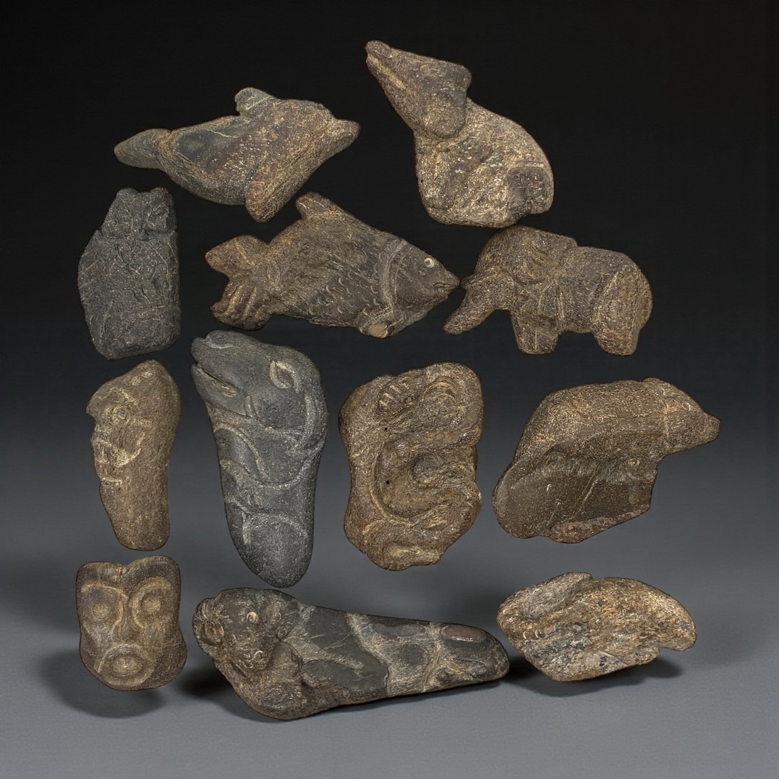A Near Eastern Bone Amulet Group, 3rd-1st Millennium BCE, 73W: The group comprises twelve small amulets carved from bone, worked in low relief and exhibiting a range of schematic zoomorphic and anthropomorphic forms; the material shows natural tonal variation fro