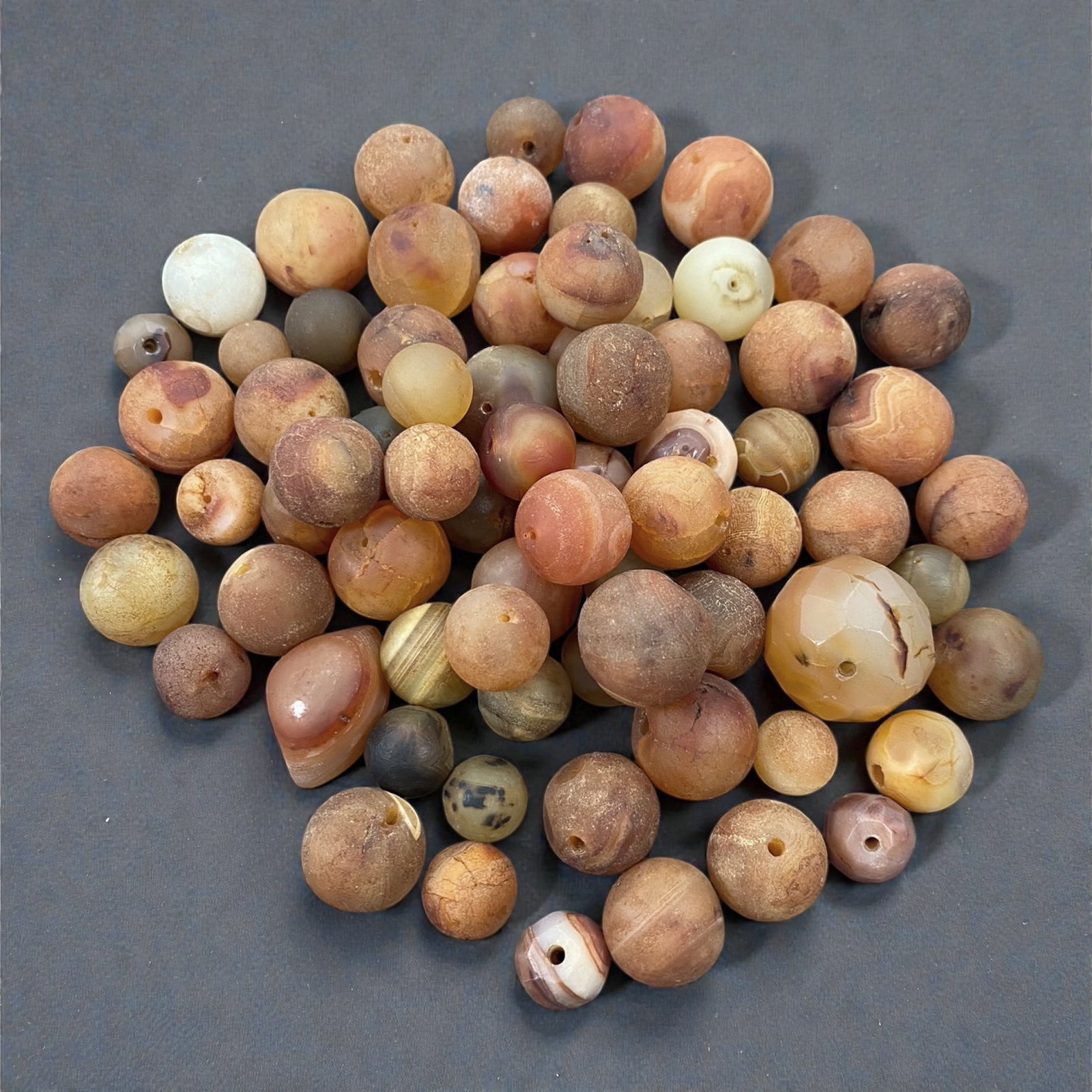A Tibetan Carnelian Bead Group, 18th-19th Century, 85W: Comprising seventy-two drilled carnelian beads of predominantly spherical and slightly irregular form, the group exhibits a broad spectrum of warm tonal variation ranging from pale cream and honey to 