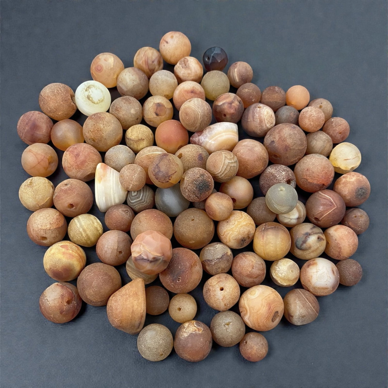 A Tibetan Carnelian Bead Group, 18th-19th Century, 83W: Comprising eighty-nine drilled carnelian beads of spherical and slightly irregular form, the group displays a wide range of warm tonal variation from pale honey and soft orange to deeper reddish-brown