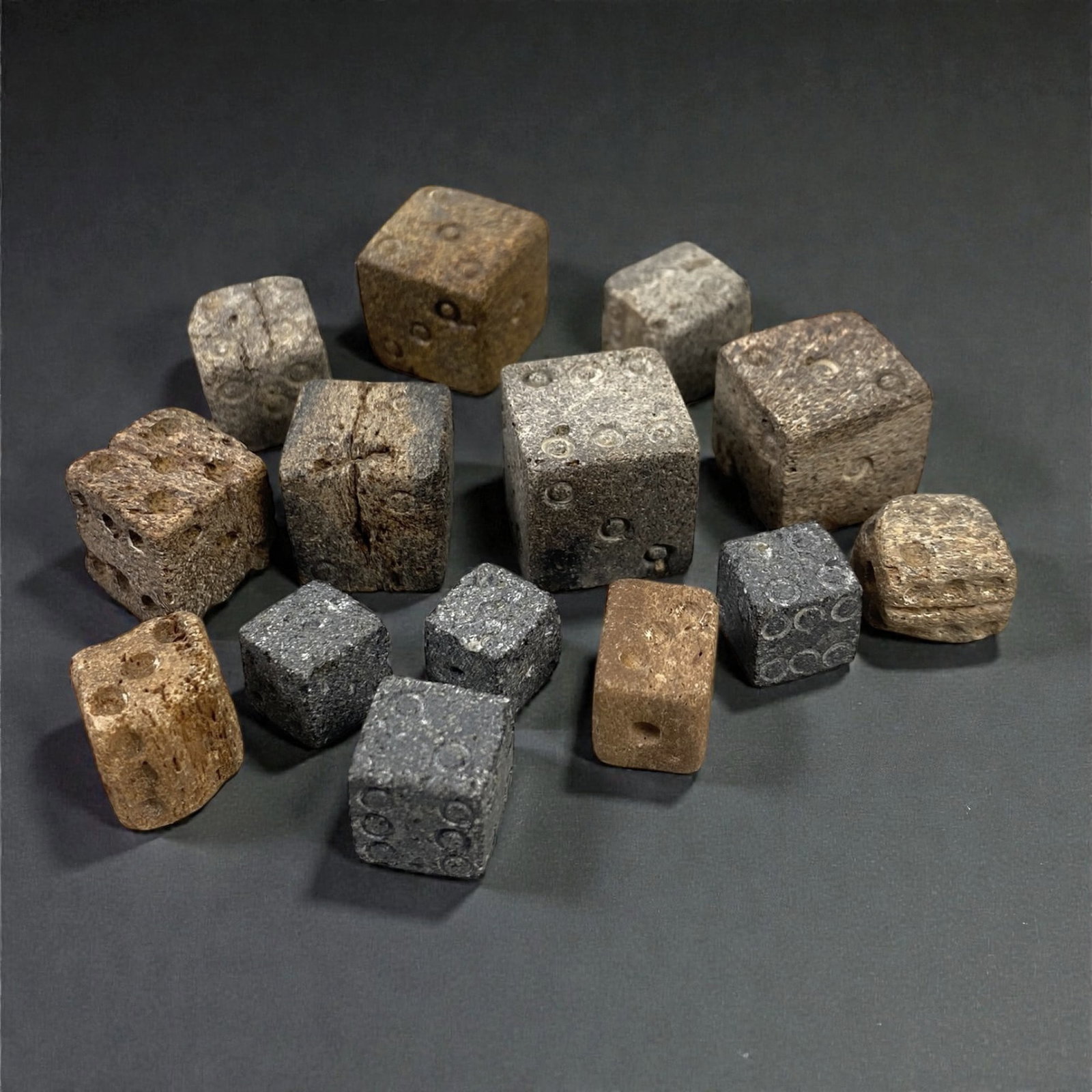 A Group of Roman Bone Dice, 1st-3rd Century CE, 47XJ: Comprising fourteen cubic dice carved from bone, each worked with drilled circular pips arranged in opposing numerical faces, the group displays slight variation in size, proportion, and surface finis