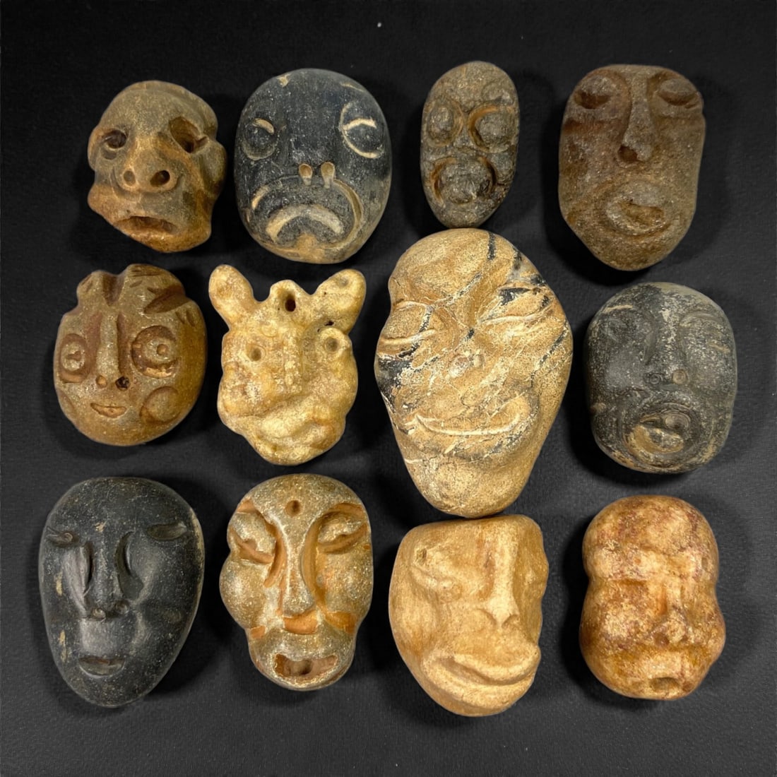 A Lot of Ancient Mediterranean Stone Maskettes, 12th-17th Century, 2.3-4cm, 46V: The group comprises lot of small maskettes carved from various stone types, including limestone and related sedimentary materials, displaying a range of natural tones from pale beige and ochre to dark