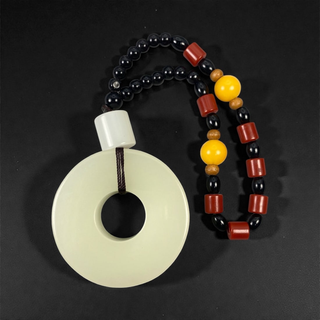 A Chinese Hetian Jade Bi Pendant, 20th Century, 86FD: Carved from pale celadon-toned Hetian jade with a uniform, softly translucent body and a smoothly polished surface. The pendant is formed as a flat circular disc with a central perforation, correspond