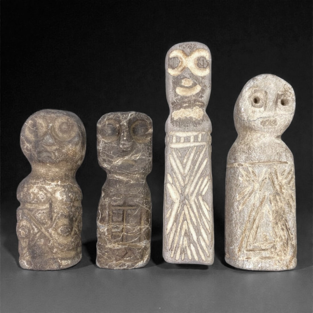 A Near Eastern Stone Idol Group, Medieval Period, 65Z: Carved from light to medium-grey stone with natural inclusions, surface pitting, and areas of abrasion, the group comprises four anthropomorphic stone idols of compact, tapering form. The figures are