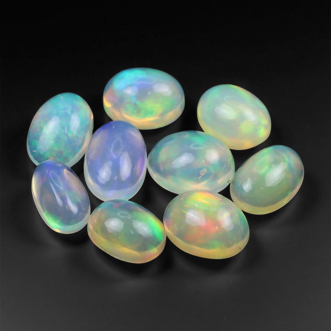 12.85 Carats Neon Play-of-Color Opal Selection - Natural Ethiopian Cabochons - 8 to 10 mm, 12XE: This luminous selection of opals radiates a dynamic spectrum of neon hues, with flashes of electric green, vivid orange, and spectral blue dancing across each dome. Their translucent base allows the i