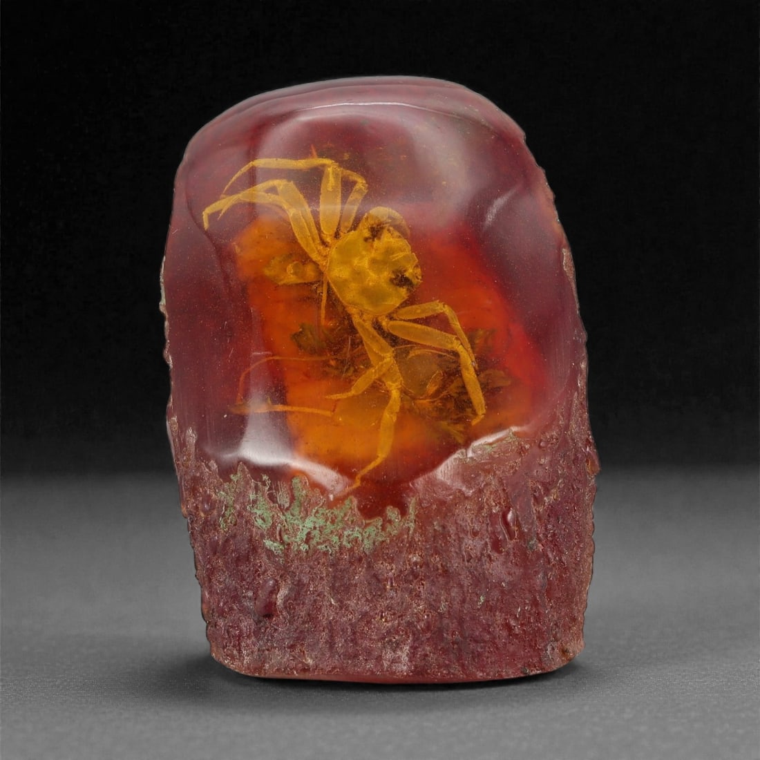 An Amber Resin Display with Encased Crab, 20th Century, 69YB: Formed from translucent reddish-brown amber resin, the object is shaped as a freestanding rectangular block with a rounded upper edge and an irregular, textured base left partially unpolished. Encased