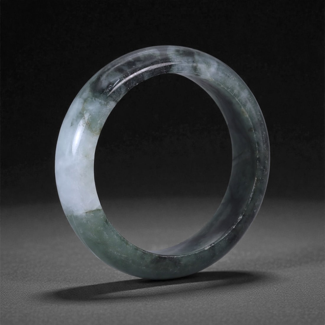 A Chinese Jadeite Bracelet Bangle, 5.3cm Inner Diameter, 9WE, 9WE: Carved from jadeite, the bracelet is formed as a continuous circular bangle with a rounded cross-section and a uniformly polished surface. The interior and exterior edges are smoothly finished, indica