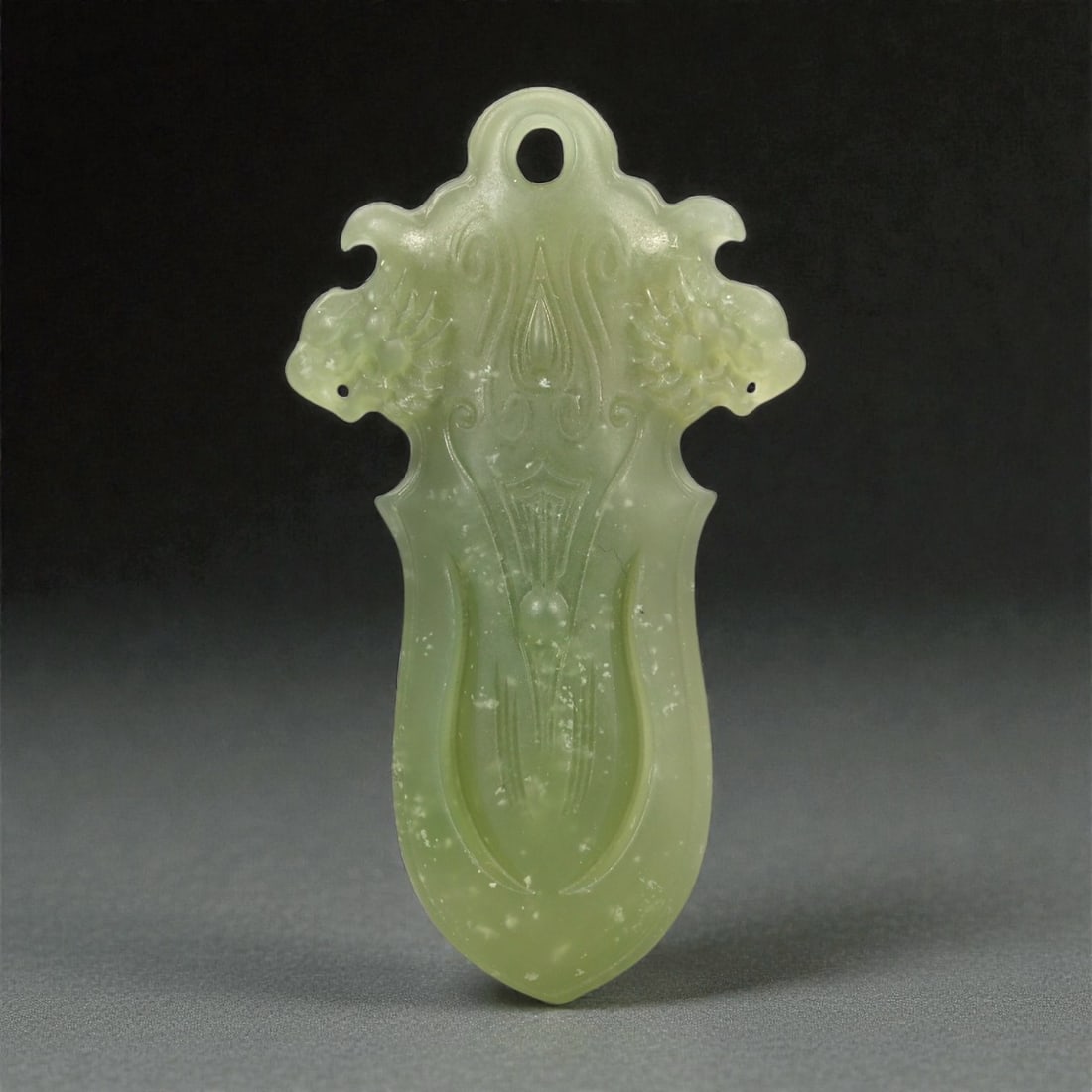 A Chinese Jade Stylized Fruit Pendant, 20th Century, 35FA: Carved from pale green jade with areas of translucency and scattered natural inclusions, the object is formed as a vertically oriented pendant with a pierced suspension hole at the upper edge. The com