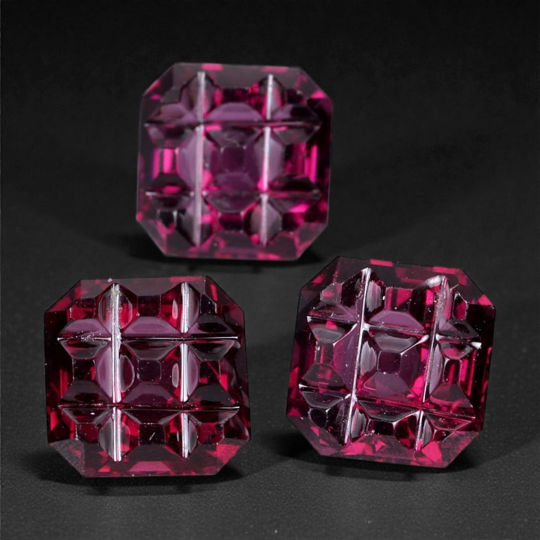 9.28 Carats Vivid Magenta Garnet Trio - Natural Mozambique Stones 7-8mm, 69XH: A striking trio of magenta garnets, these stones are masterfully cut with deep geometric concave facets that create dramatic internal reflections and architectural brilliance. The intense fuchsia-pink