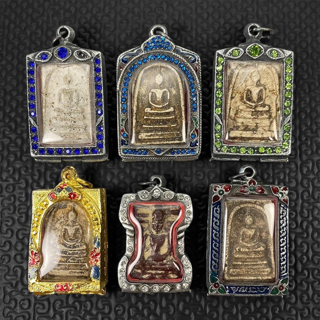 A Group of Six Thai Buddhist Amulets, 20th Century, 15XJ: Comprising six Thai Buddhist amulets formed from pale beige to buff and brown clay-based or composite materials, each molded in shallow relief and depicting a seated Buddha in meditation posture on a