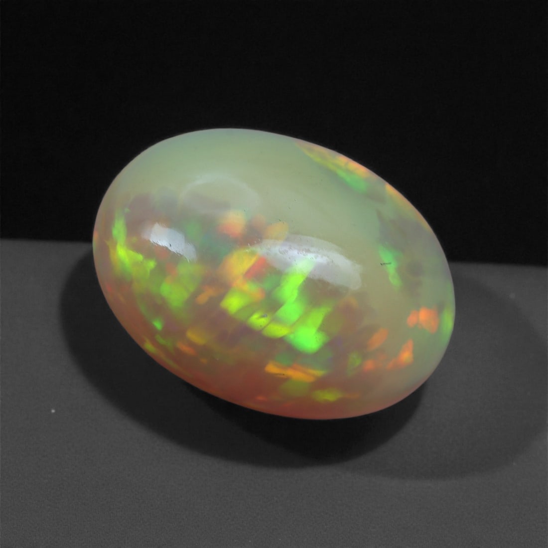 3.11 Carats Play-of-Color Welo Opal - Natural Ethiopian Gem 13x9mm, 42XA: This captivating Welo opal gleams with a luminous cascade of multi neon color that ripple across the stone's surface with every movement. The play-of-color is vivid and well-distributed, presenting a