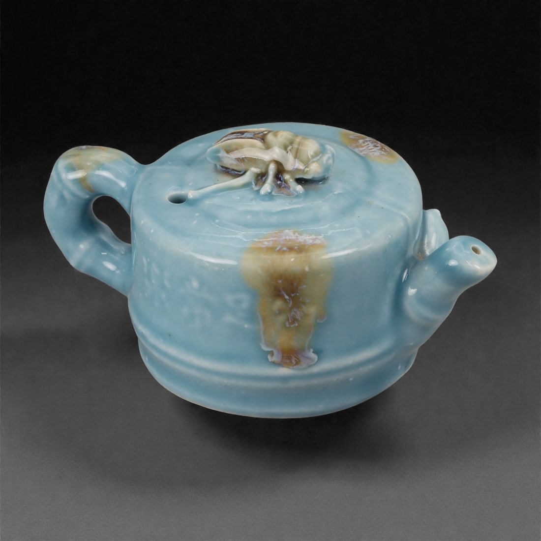 A Chinese Glazed Ceramic Teapot-Form Snuff Bottle, 20th Century, 66FG: Modeled from a ceramic body and covered with a pale blue glaze with areas of buff and cream-colored pooling, the vessel is formed in the shape of a miniature teapot. The rounded body is fitted with an