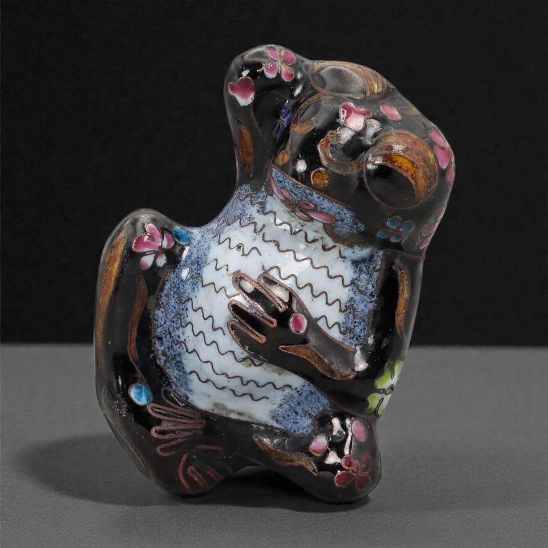 A Chinese Enamel Frog Effigy, 20th Century, 10FH: Modeled as a stylized frog shown seated upright with the head tilted upward and forelimbs drawn toward the chest, the effigy is formed from a metal core and decorated with painted enamel rather than c