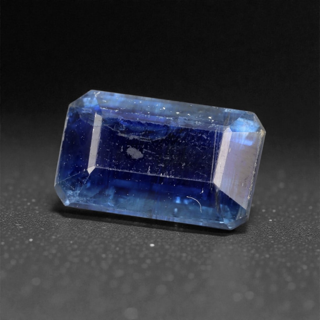 6.46 Carats Deep Blue Kyanite Emerald Cut - Natural Nepalese Stone, 51XK: This striking kyanite presents a rich, inky blue tone with flashes of steel and sapphire hues that shift subtly with the light. Cut in a clean emerald shape, the stone shows crisp edges and a strong,