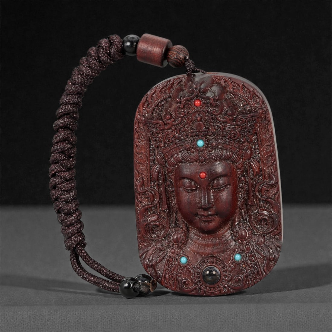 A Chinese Wood Plaque with Buddhist Figure, 20th Century, 58FD: Carved from dark reddish-brown wood with a polished surface, the plaque is rectangular with rounded corners and pierced at the top for suspension. The front is worked in relief with a frontal depictio
