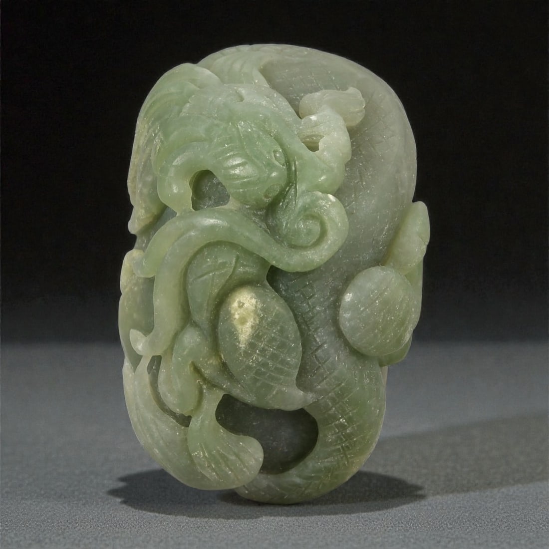 A Chinese Nephrite Jade Dragon Carving, 20th Century, 8FD: Carved from green Hetian nephrite jade with a semi-translucent body and scattered natural inclusions, the object is worked as a compact sculptural carving in the round. The composition depicts a styli