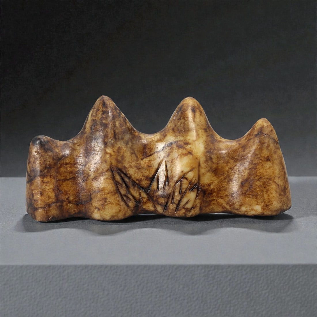 A Chinese Hardstone Brush Rest, 20th Century, 10YB: Carved from mottled brown and buff-toned hardstone with natural veining and tonal variation, the object is worked as a horizontal brush rest with an undulating upper profile formed by a series of roun