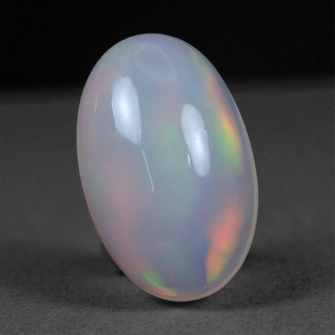 2.82 Carats Play-of-Color Welo Opal - Natural Ethiopian Gem 14x9mm, 28XC: This captivating Welo opal gleams with a luminous cascade of multi neon color that ripple across the stone's surface with every movement. The play-of-color is vivid and well-distributed, presenting a